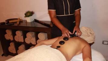 En person modtager massage med varme sten placeret på ryggen.
