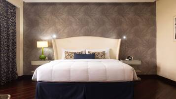 A hotel room with a large bed, two bedside tables, a lamp, and a wall with a swirling pattern.