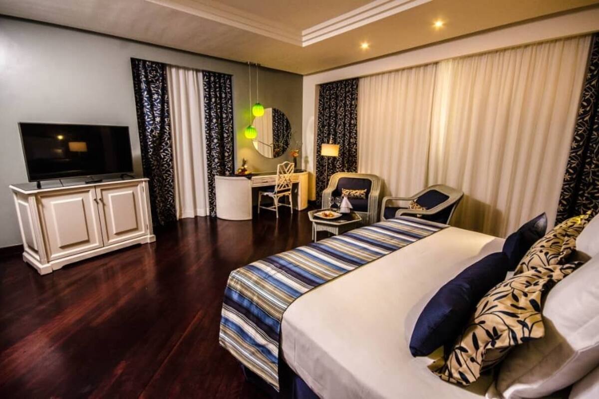 Ein Hotelzimmer mit Bett, Schreibtisch, Stuhl, Fernseher und Kleiderschrank.