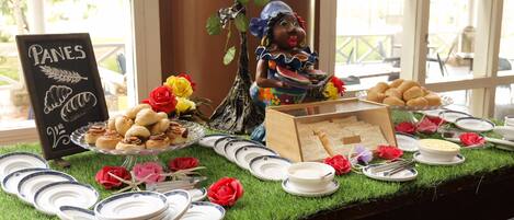 Une table de buffet avec divers plats, assiettes et un panneau indiquant « PANES ».