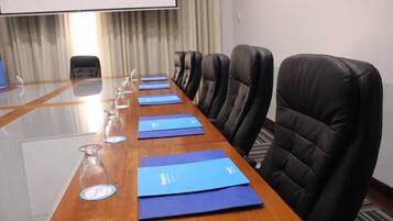 A conference room with a long table, blue folders, and glass bottles.