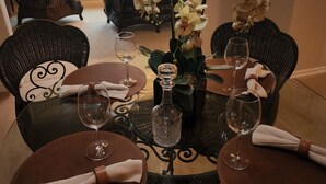 A dining table set with wine glasses, a vase with orchids, and a bottle of water. - Lakehouse on Ky Lake-Lakefront, Park like backyard, Covered Dock, Firepit. (Benton)
