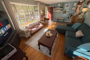 A living room with a sofa, a coffee table, a TV, and a window with curtains. - Saratoga Excitement Meets Peaceful Retreat- 10 mins to the track! (Greenfield Center)