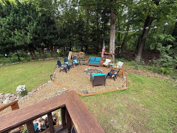 Un área de estar al aire libre con sillas Adirondack, un sofá azul y un brasero.