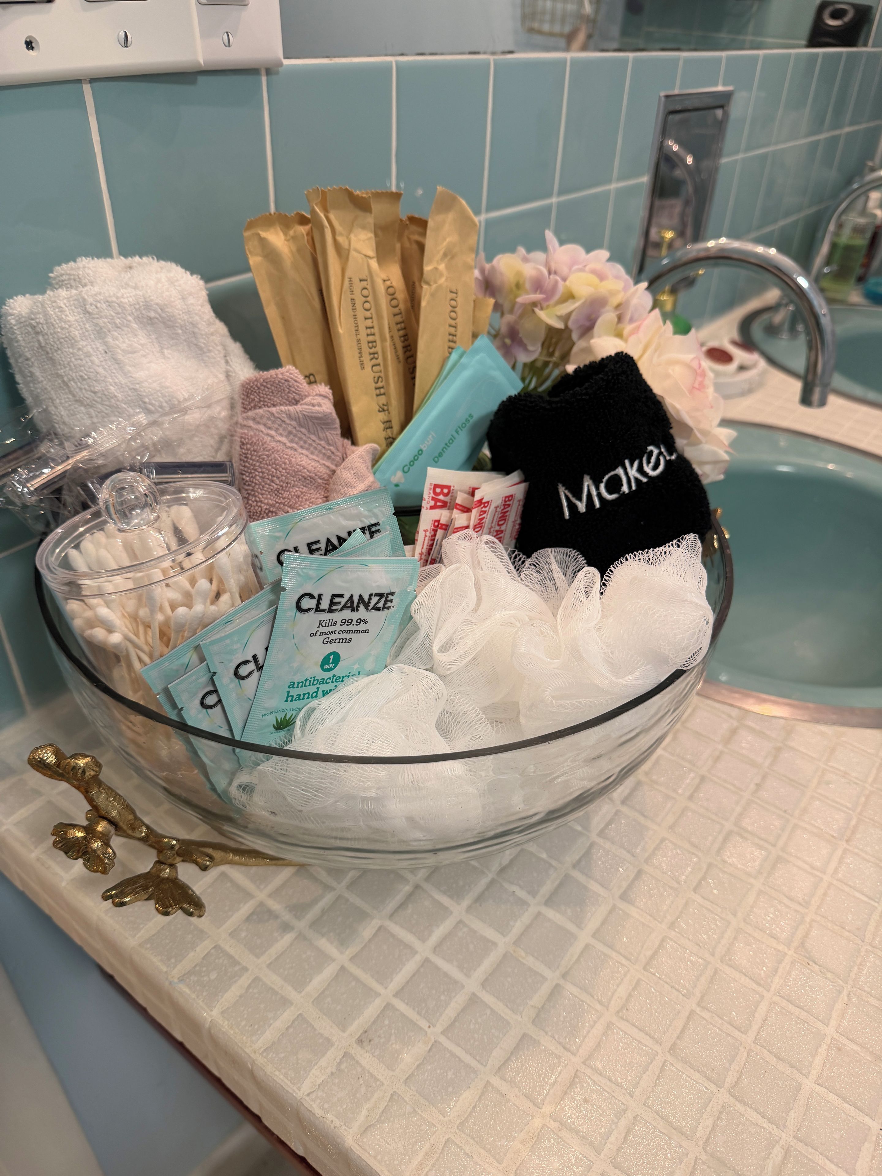 A glass bowl containing toiletries on a bathroom counter.