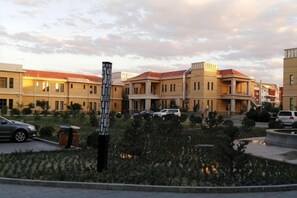 Um complexo habitacional com várias construções de dois andares, área de estacionamento e um jardim paisagístico com um elemento central.