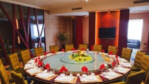 Une salle de conférence avec une table ronde, des chaises jaunes et un arrangement floral au centre.