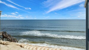 Vista a la playa con una escalera de madera que baja a la arena.