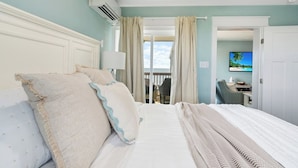 Una habitación de hotel con una cama grande, un balcón, un escritorio y una televisión.
