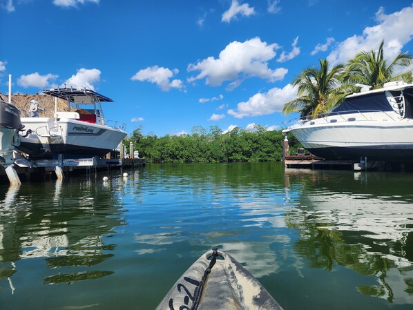 A marina with boats docked, calm water, and a clear sky.