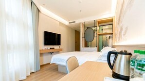 A hotel room with a bed, a TV, a coffee maker, and a table with breakfast items. - Dali Canger Yilong Hotel (Dali City)