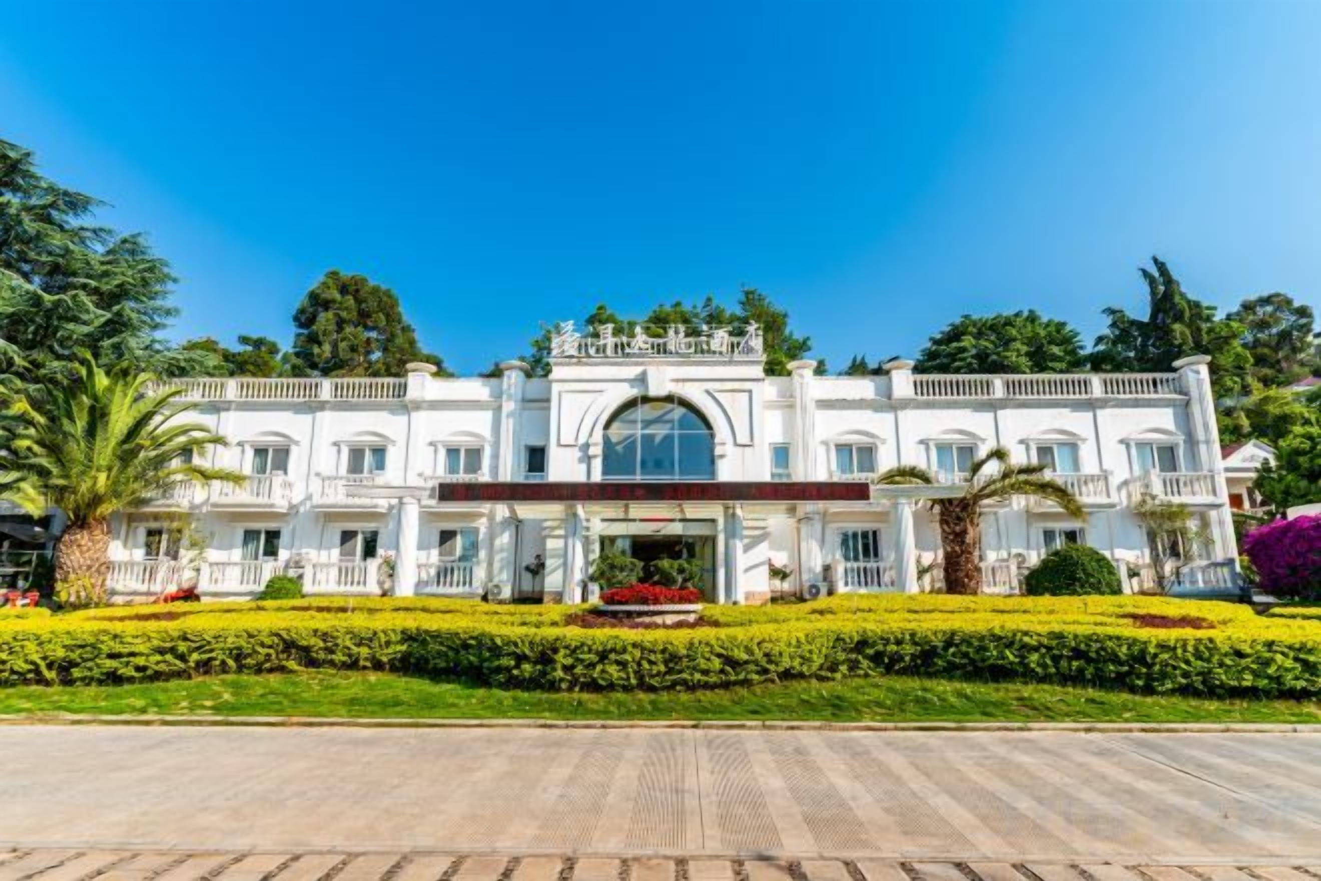 Un edificio grande y blanco con fachada simétrica, múltiples ventanas y una entrada central.