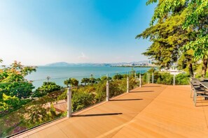 Une terrasse en bois offrant une vue sur la mer et le paysage urbain au loin.