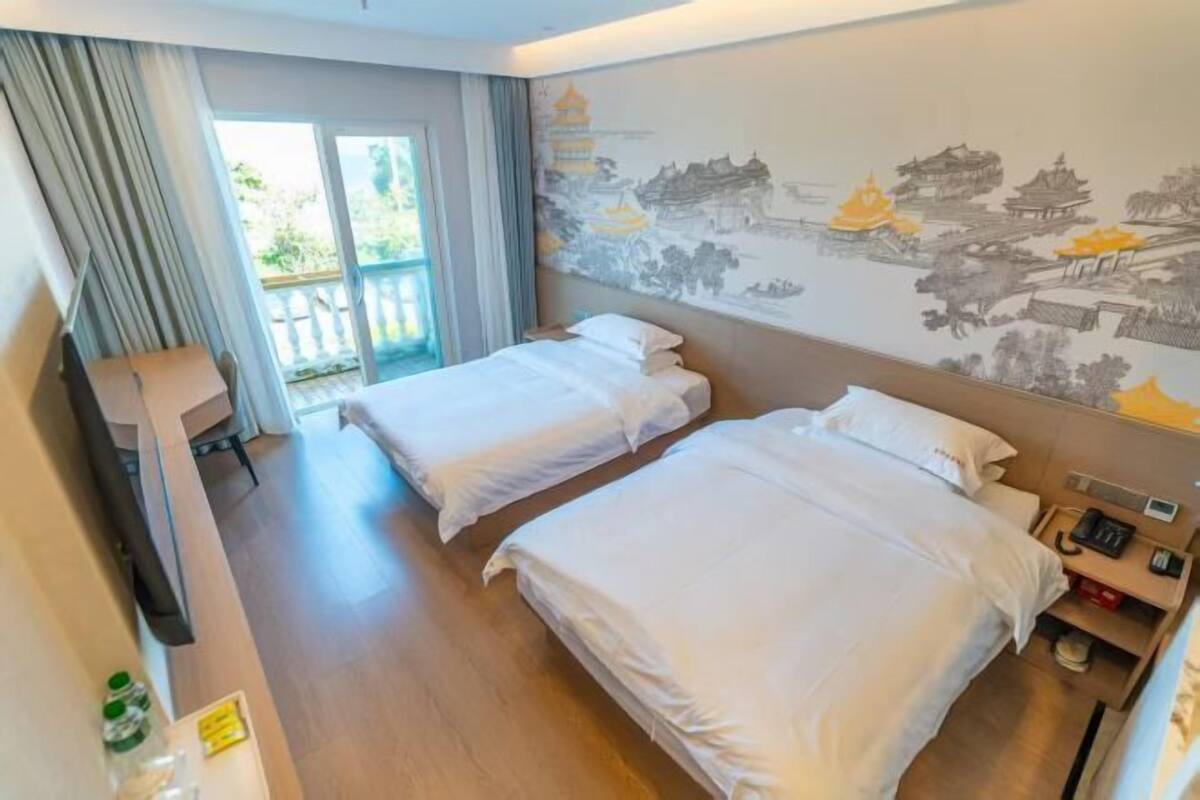 A hotel room with two beds, a balcony, and a wall with traditional artwork.