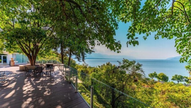 A wooden deck with outdoor furniture overlooking a body of water and greenery. - Dali Canger Yilong Hotel (Dali City)