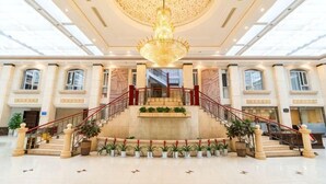 A grand lobby with a central staircase, a chandelier, and potted plants. - Dali Canger Yilong Hotel (Dali City)