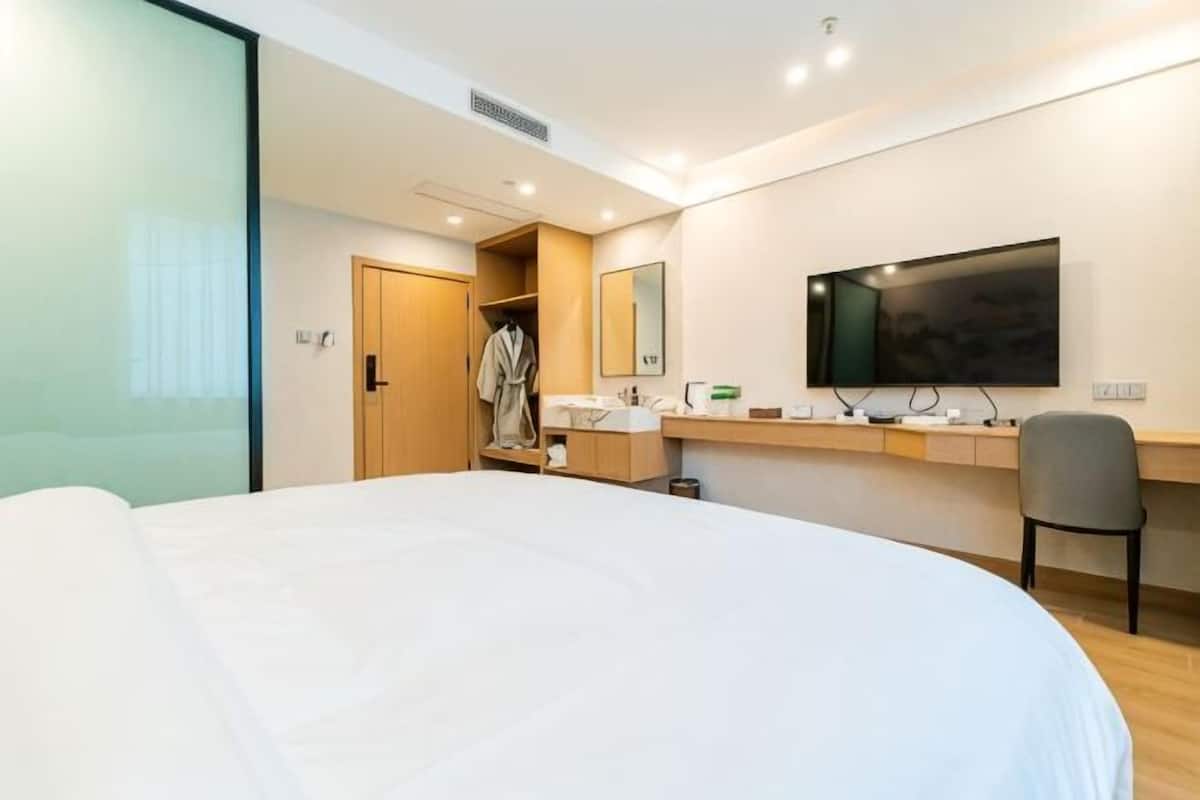 A hotel room with a bed, a desk with a computer, a mirror, and a television.