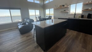 A spacious kitchen with a large island, multiple windows, and a view of the water.
