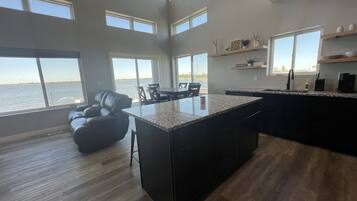 A spacious kitchen with a large island, multiple windows, and a view of the water.