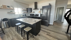 A modern kitchen with a large island, stainless steel appliances, and a hardwood floor.