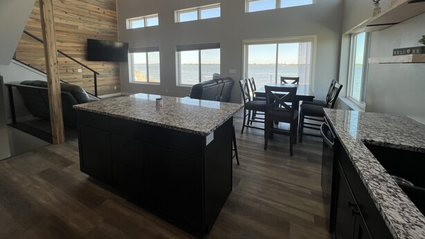 A spacious kitchen with a large island, multiple windows, and a view of the sea.