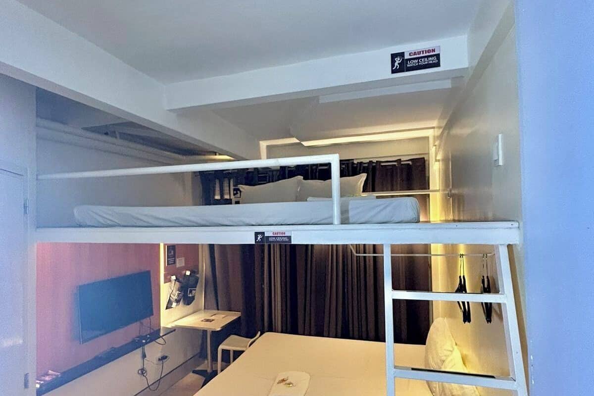 A bunk bed room with a television, a desk, and a caution sign for low ceiling.