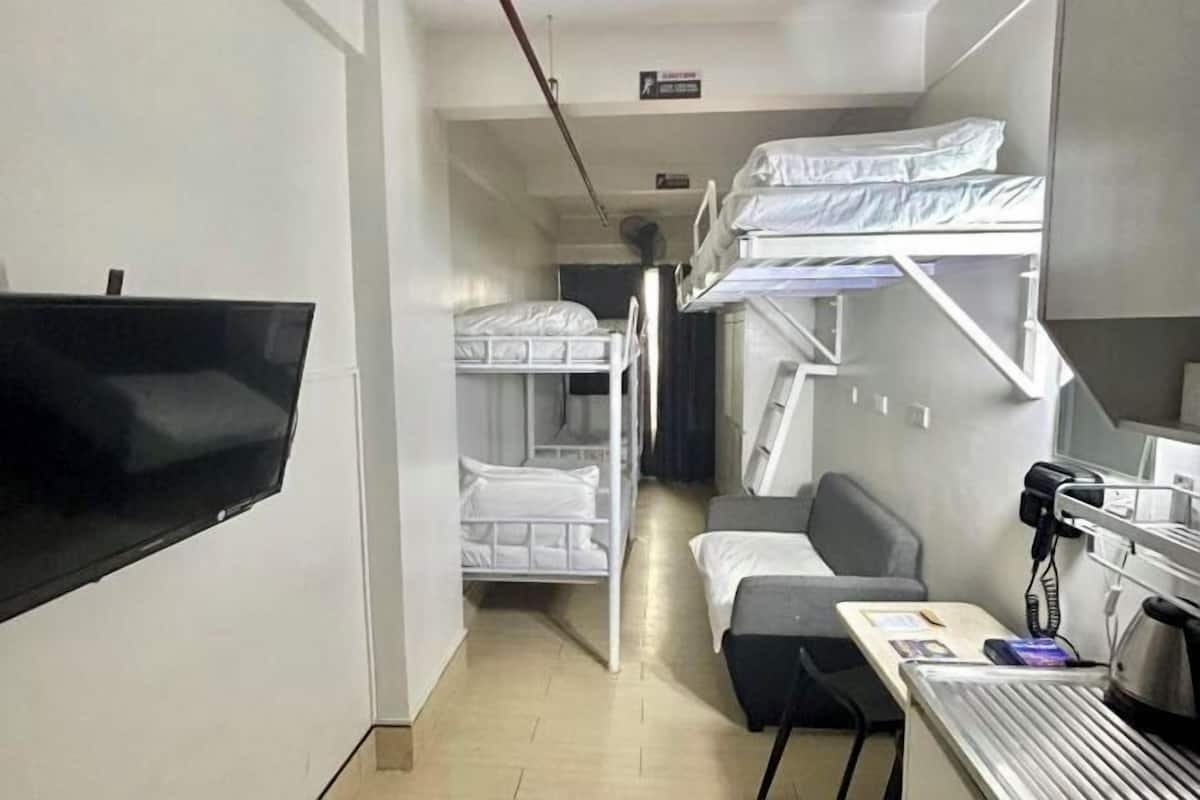 A room with bunk beds, a desk with a computer, and a flat-screen TV.
