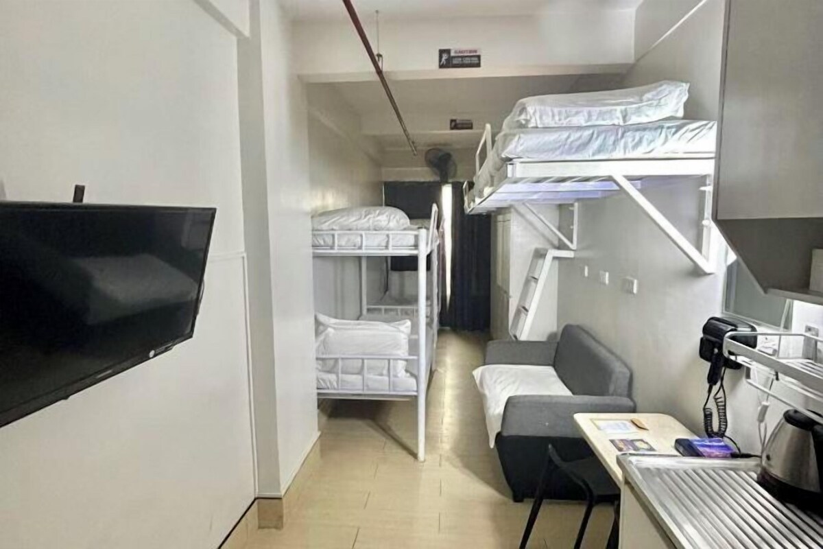 A room with bunk beds, a desk with a computer, and a flat-screen TV.
