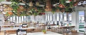 A restaurant with tables and chairs, hanging plants, and birdcages. - Selah Lofts Pasay (Pasay)
