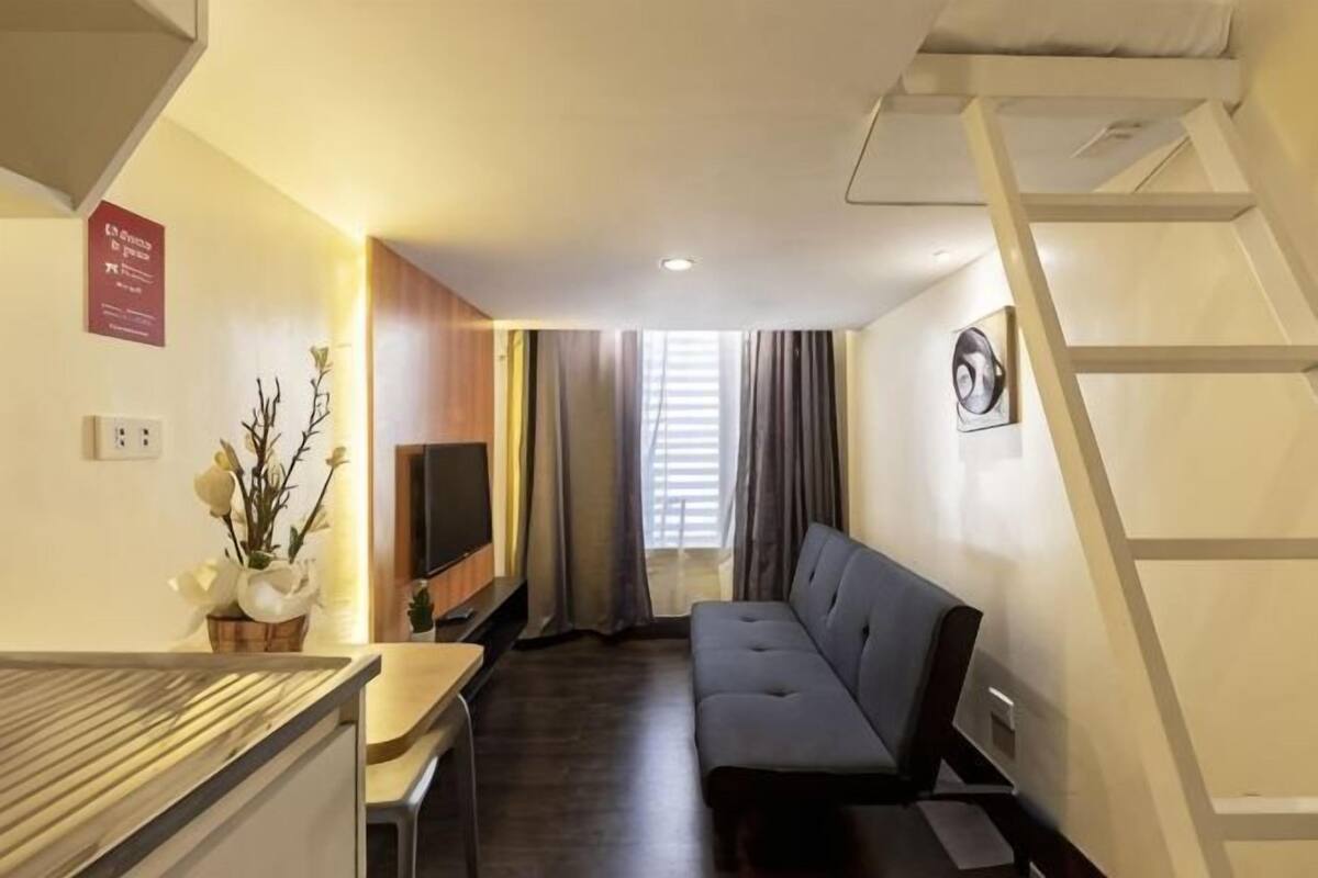 A compact living space with a sofa, a TV, a small table, and a staircase.