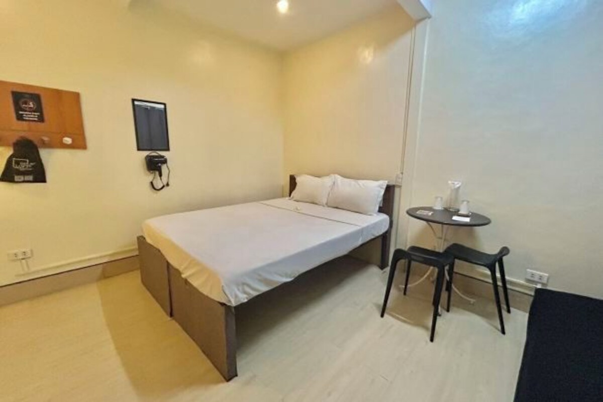 A small, clean room with a bed, a small table, and a chair.
