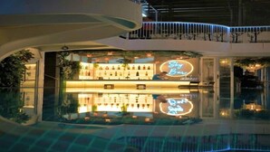 A bar with a neon sign, a pool, and a reflection of the bar in the water. - Selah Lofts Pasay (Pasay)