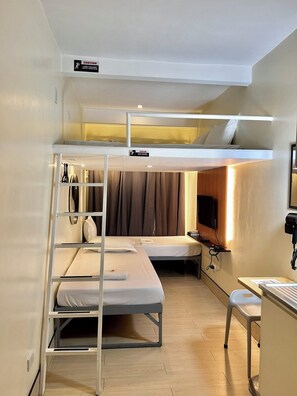 A bunk bed room with a desk, a chair, and a TV. - Selah Lofts Pasay (Pasay)