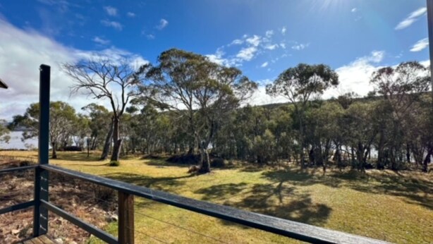 A fenced outdoor area with trees and a clear sky. - Currawong Cottage - Fishing Paradise (Anglers Reach)