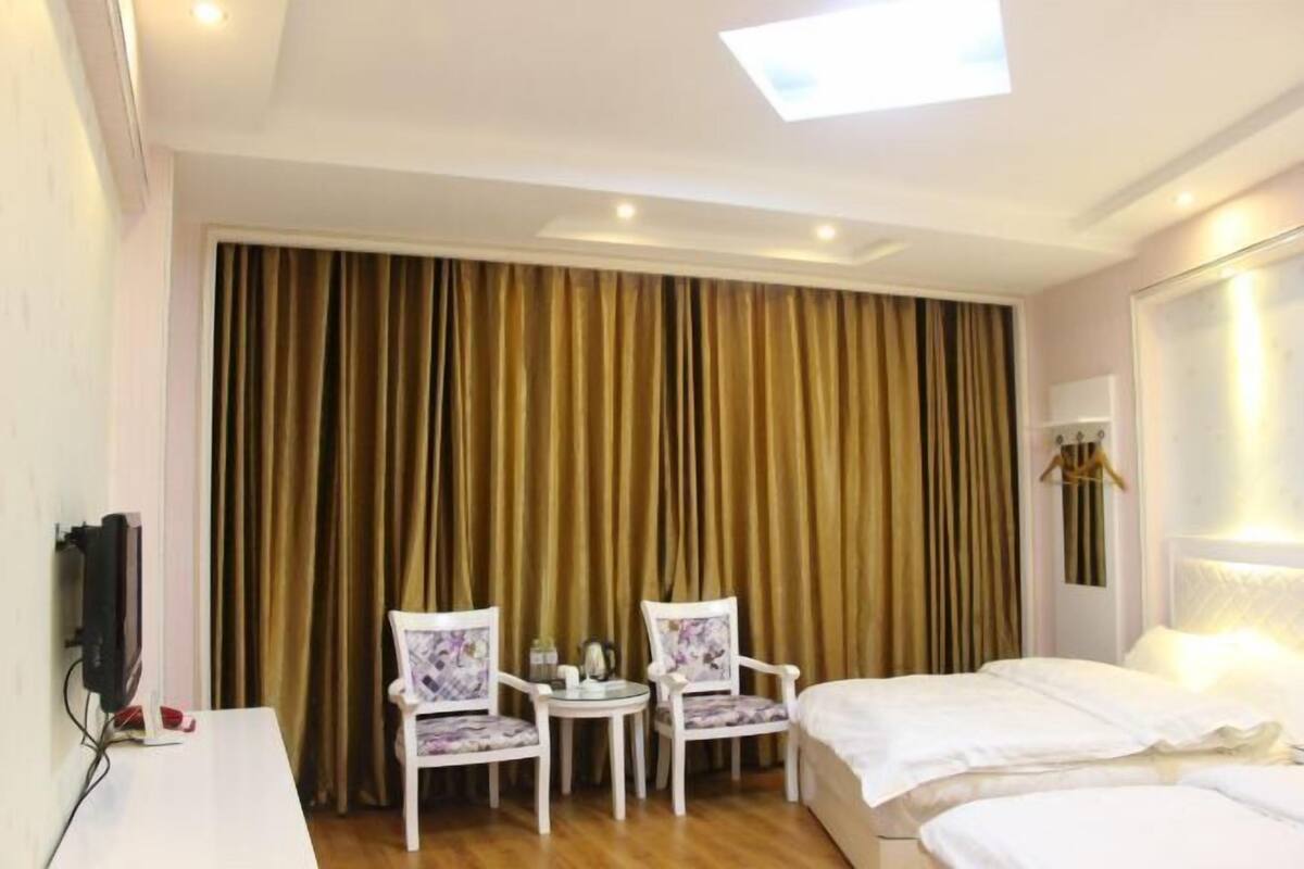 A hotel room with a bed, two chairs, a small table, and a TV.