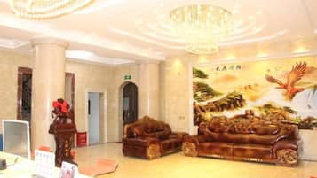 A lobby with a chandelier, a reception desk, and a large mural.