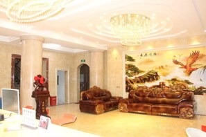 A lobby with a chandelier, a reception desk, and a large mural. - Dongri Yanguang Hotel (Shangri-La)