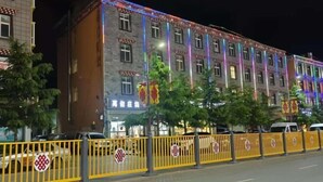 Un edificio de varios pisos con un estilo arquitectónico tradicional, que presenta una serie de ventanas y un escaparate con señalización.