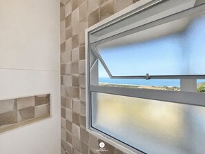 A window with a view of the ocean and a tiled wall. - Paraíso do Coral - Vista Mar - Garopaba (Paulo Lopes)