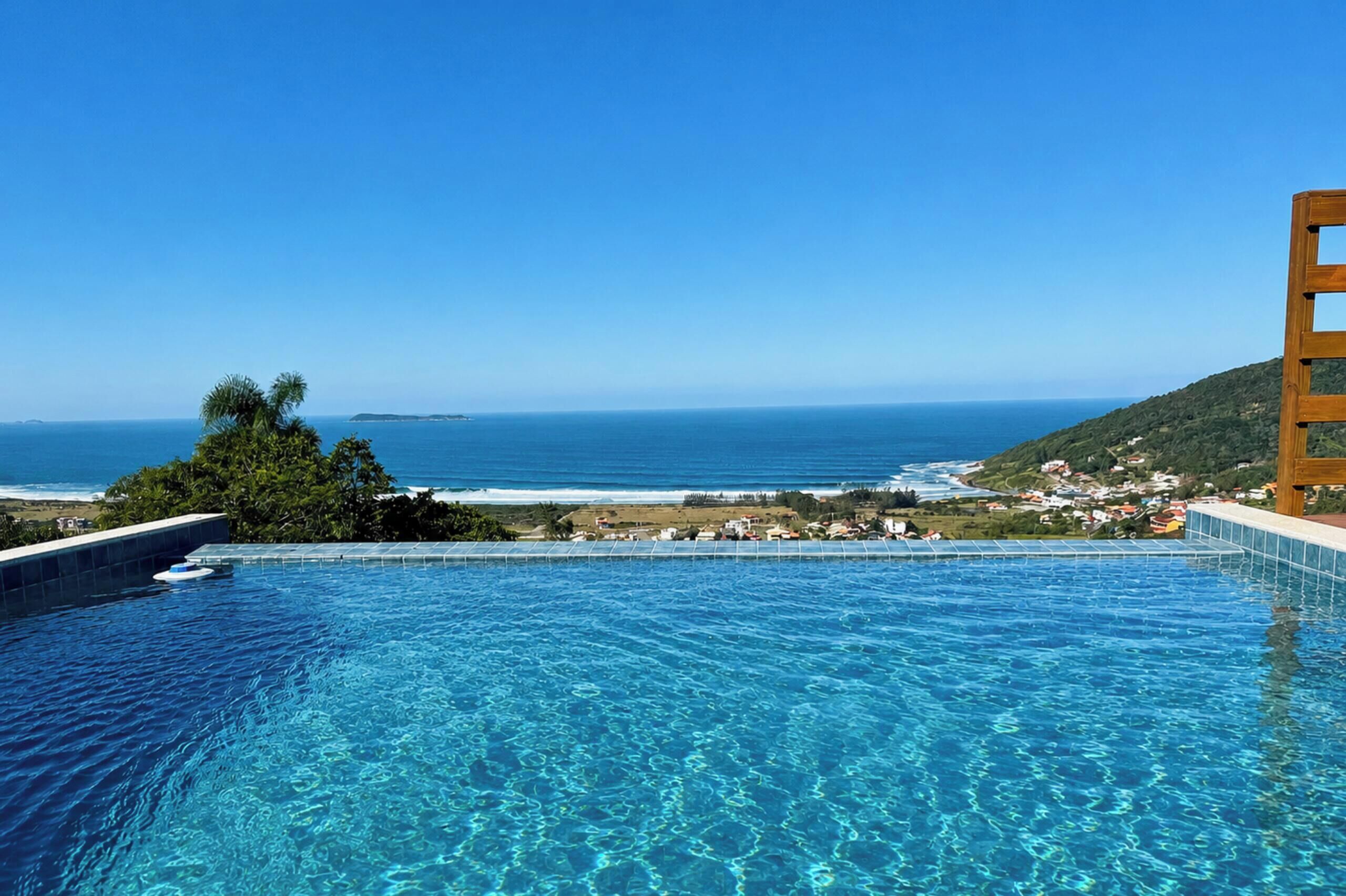An infinity pool with a view of the ocean and a hillside.