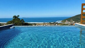 An infinity pool with a view of the ocean and a hillside. - Paraíso do Coral - Vista Mar - Garopaba (Paulo Lopes)