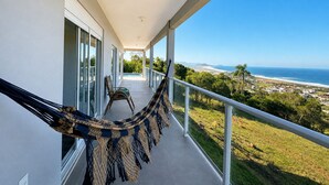 A balcony with a hammock, a view of the ocean, and a clear sky. - Paraíso do Coral - Vista Mar - Garopaba (Paulo Lopes)