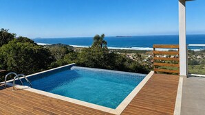 A swimming pool with a view of the ocean and a wooden deck. - Paraíso do Coral - Vista Mar - Garopaba (Paulo Lopes)