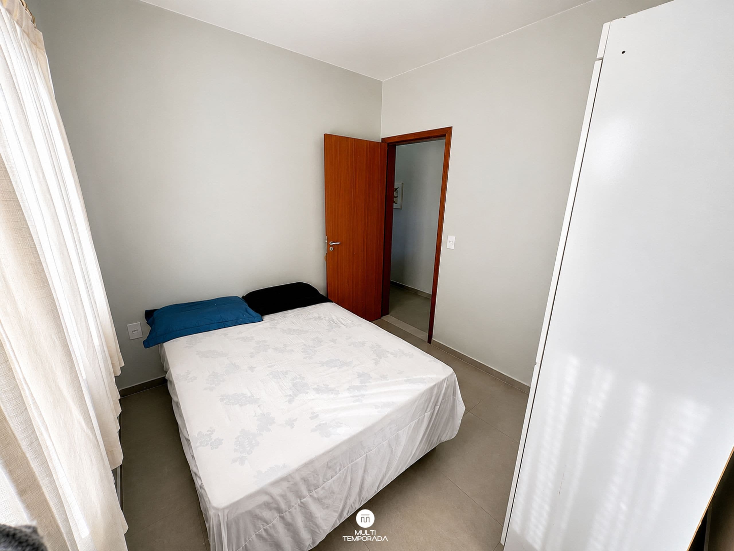 Une chambre à coucher avec un lit, une porte et une armoire blanche.