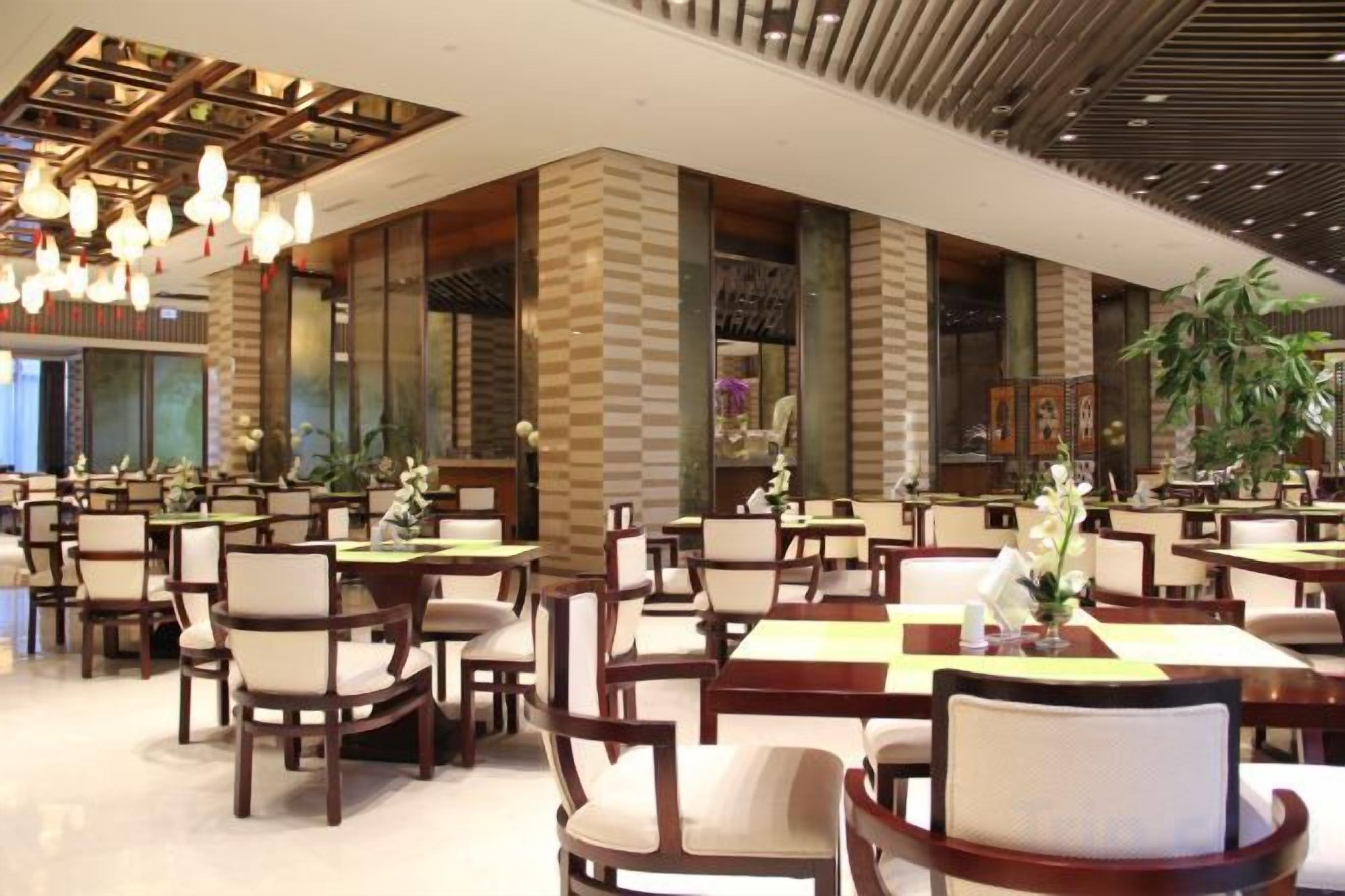 Un comedor amplio con varias mesas y sillas, techos altos con vigas de madera y luminarias decorativas.