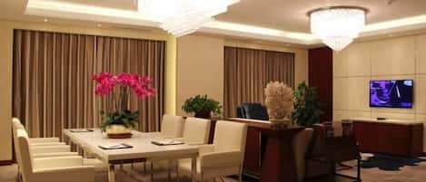 A modern hotel room with a dining area, a seating area, and a television.