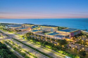 Un complejo hotelero con varias construcciones, una zona de estacionamiento y vista al mar.