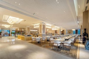 Un amplio vestíbulo de hotel con una larga zona de comedor, diversas opciones de asientos y una barra central.