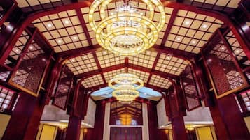 A traditional interior with a high ceiling, ornate wooden lattice, and a central chandelier.
