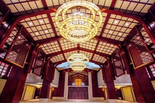 A traditional interior with a high ceiling, ornate wooden lattice, and a central chandelier.